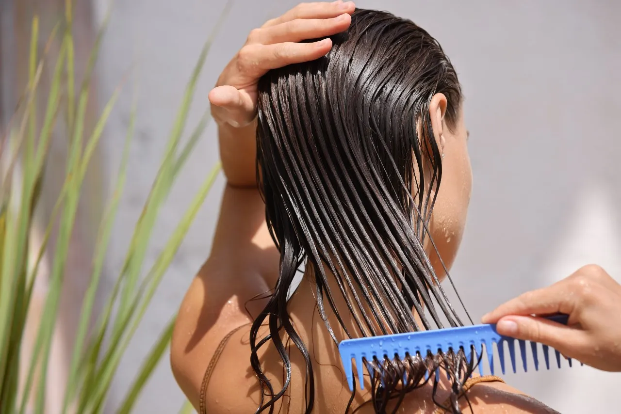 Na obrázku jue žena ktorá si češe mokré vlasy 